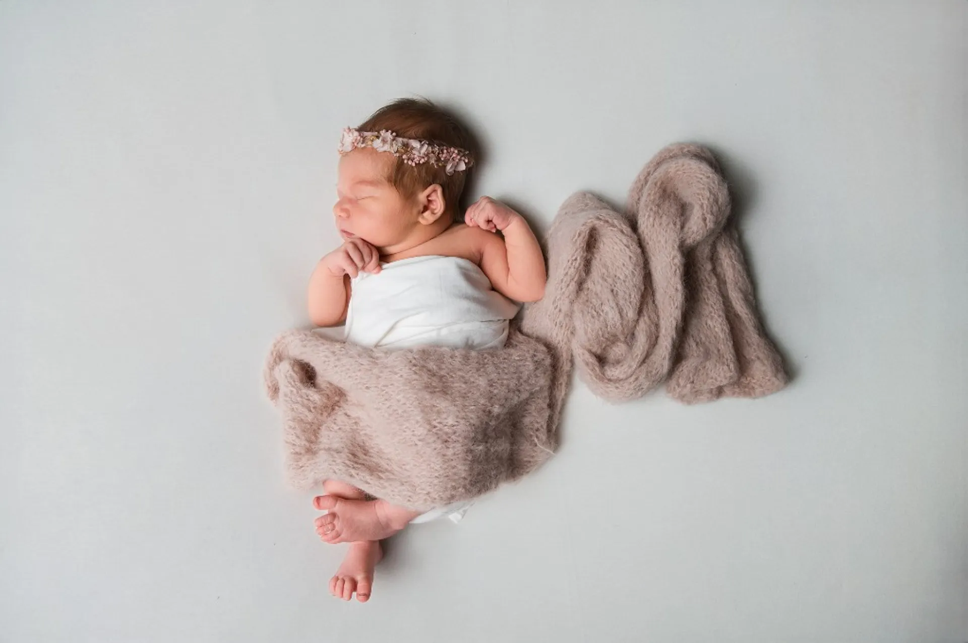 Alvó újszülött baba virágos fejpánttal — természetes újszülött fotózás